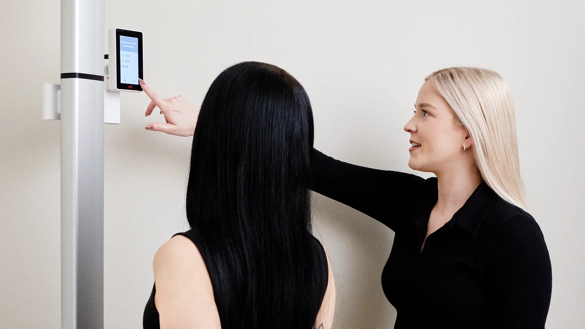 A staff member showing a patient the body composition scanner display.